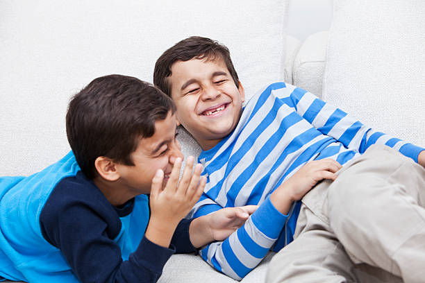 Twin boys acting silly Brazilian twin boys (8 years) having fun, laughing hysterically.  Focus on boy in striped shirt. child laughing hysterically stock pictures, royalty-free photos & images