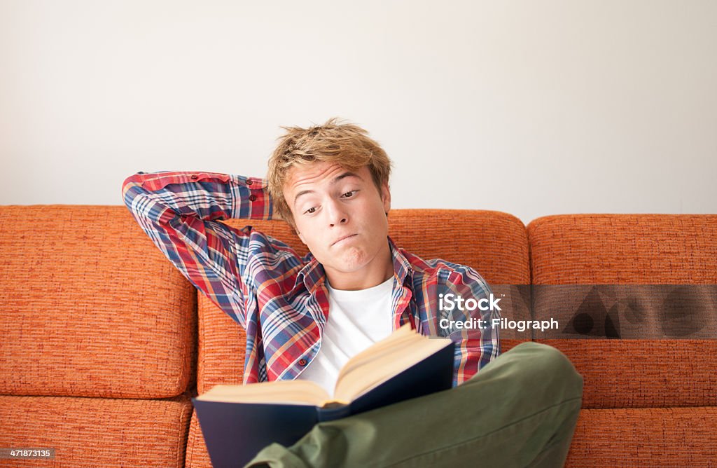 Reading Book teenager reading a blue book on confortable sofa at home 14-15 Years Stock Photo