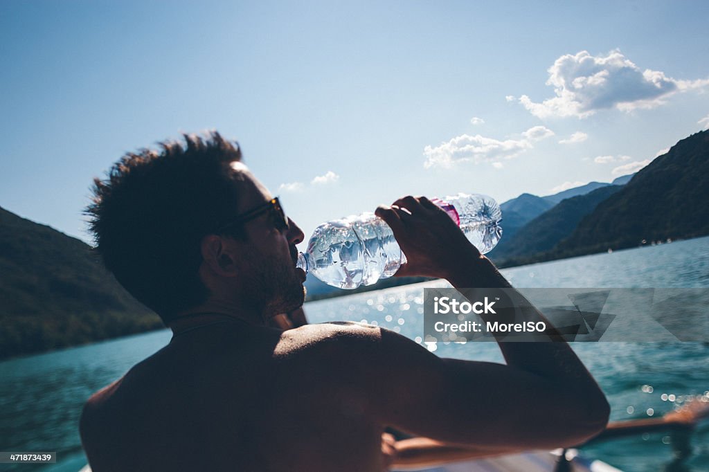 Uomo beve da una barca - Foto stock royalty-free di 25-29 anni