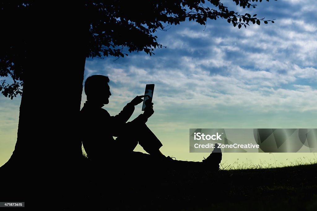 Man silhouette sitting under tree using tablet outdoor 25-29 Years Stock Photo