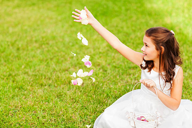 Flower Girl Throwing Petals While Sitting In Garden Happy flower girl throwing petals while sitting in garden. Horizontal shot. flower girl stock pictures, royalty-free photos & images