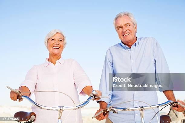 Foto de Sênior Casal Com Bicicletas Olhando Longe De Casa Contra O Céu Limpo E Azul e mais fotos de stock de 60 Anos