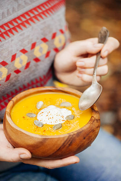 istock Woman holding pumpkin soup in a rustic bowl outside 471874443