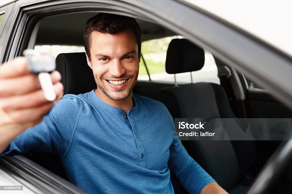 Proud new car owner Smiling male sitting in his car holding up his car keyshttp://195.154.178.81/DATA/istock_collage/1192584/shoots/784612.jpg Adult Stock Photo