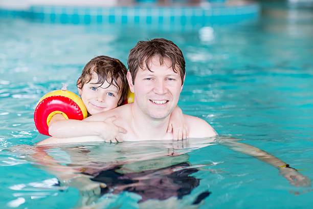 istock Young dad teaching his little son to swim indoors 471875580