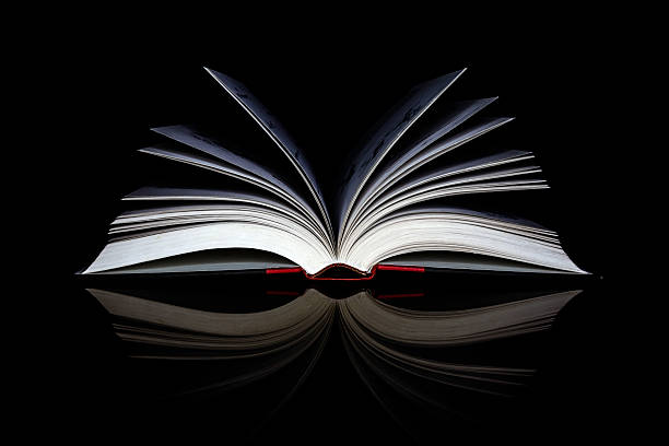 Open Book An open book resting on its spine, reflected in a black background. In a world of  e-book readers, traditionally bound books still hold their charm and character. With less and less usage in modern schools, they still express ideas of study, learning and wisdom. handbook book hardcover book red stock pictures, royalty-free photos & images