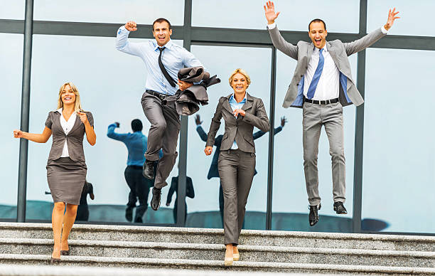 Four ecstatic business people outdoors. Two businessmen are jumping.   