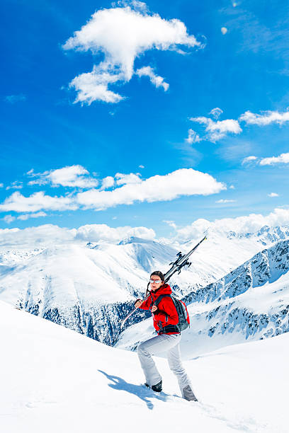 Backcountry splitboarder ascends mountain in fresh powder snow, British Columbia