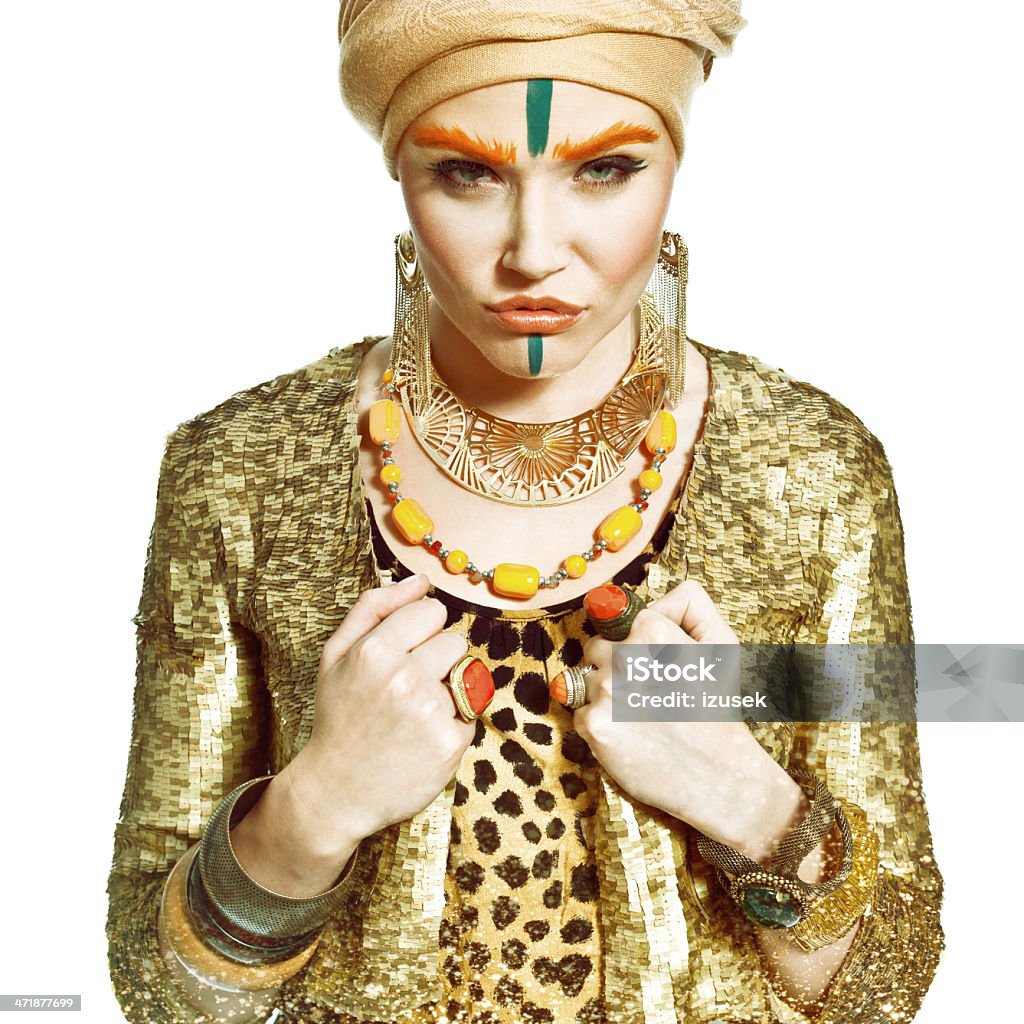 Exotic Style Woman, Fashion Portrait Portrait of young woman wearing turbane and gold jewlery and clothes, looking at camera. Studio shot on a white background. 20-24 Years Stock Photo
