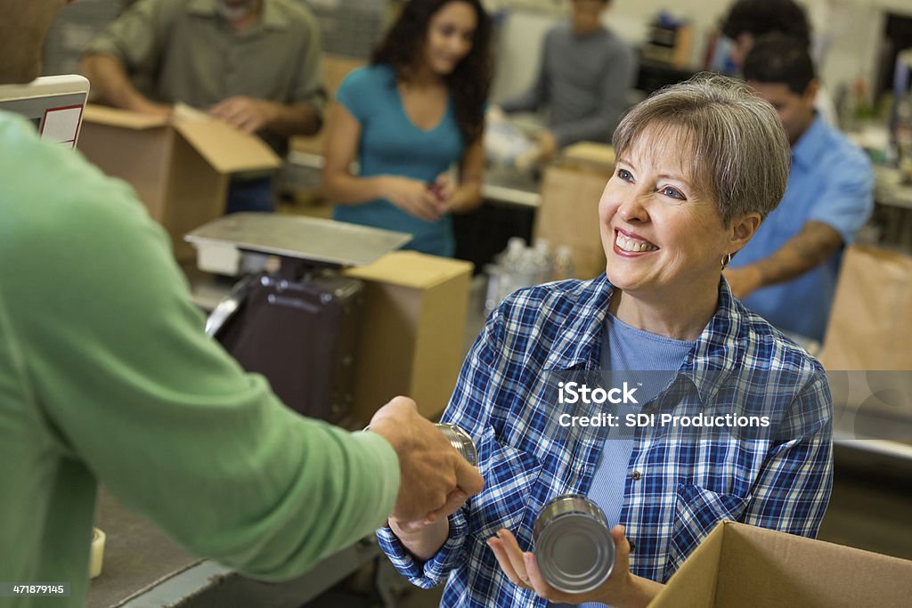 Senior Frau empfangende Spenden im food bank Sortierung center - Lizenzfrei Beengt Stock-Foto