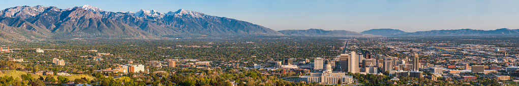 Blue skies and snow capped mountains above the landmarks of Salt Lake City, from the leafy suburbs and University campus to the monument dome of the State Capitol and the ornamental spires of the Mormon Temple surrounded by the skyscrapers of downtown, Utah, USA. ProPhoto RGB profile for maximum color fidelity and gamut.
