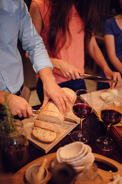 istock Man cutting bread for dinner with friends 471881514