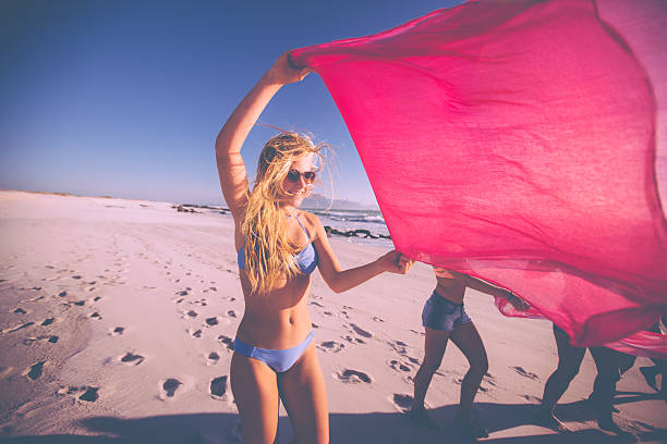 istock Girl standing on a beach flying a pink cloth 471881574