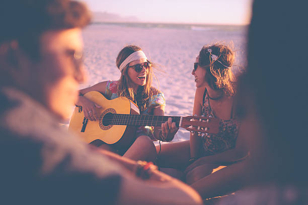niña tocando la guitarra para sus amigos en un beachparty - beach party friendship teenage girls fotografías e imágenes de stock