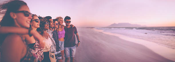 foto panorâmica de uma fileira de amigos assistindo o pôr-do-sol - summer vacations adolescence teenager - fotografias e filmes do acervo