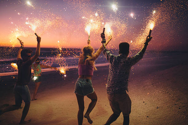Friends running on a beach with fireworks stock photo