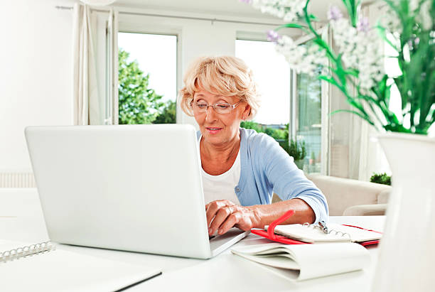 reife frau mit laptop - working at home calendar laptop women stock-fotos und bilder