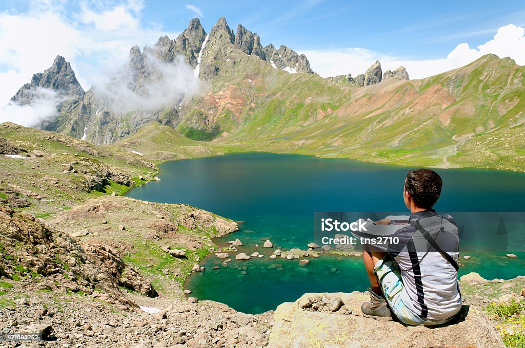 Man admiring a beautiful lake in the mountains Man admiring a beautiful lake in the mountains. Tobavarchhili lake in the mountains of Georgia 2015 Stock Photo