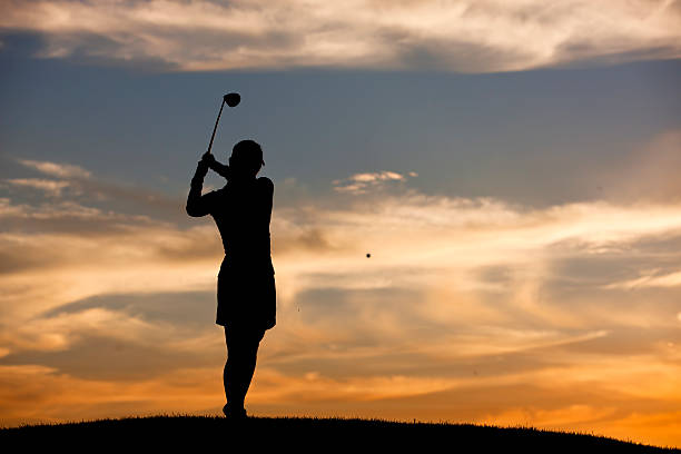 Batendo bola de golfe no pôr-do-sol. - foto de acervo