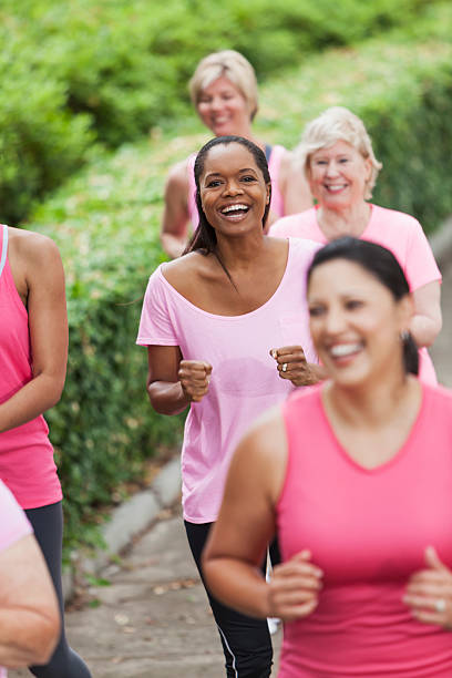 Breast cancer rally Multi-ethnic group of women (30s, 40s, 60s) wearing pink, participating in breast cancer rally. Focus on African American woman (40s) in middle. walking for a cause stock pictures, royalty-free photos & images