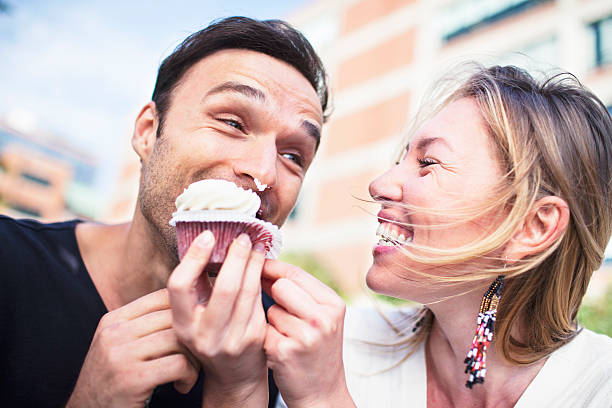 Joyful couple eating cupcake outdoors stock photo