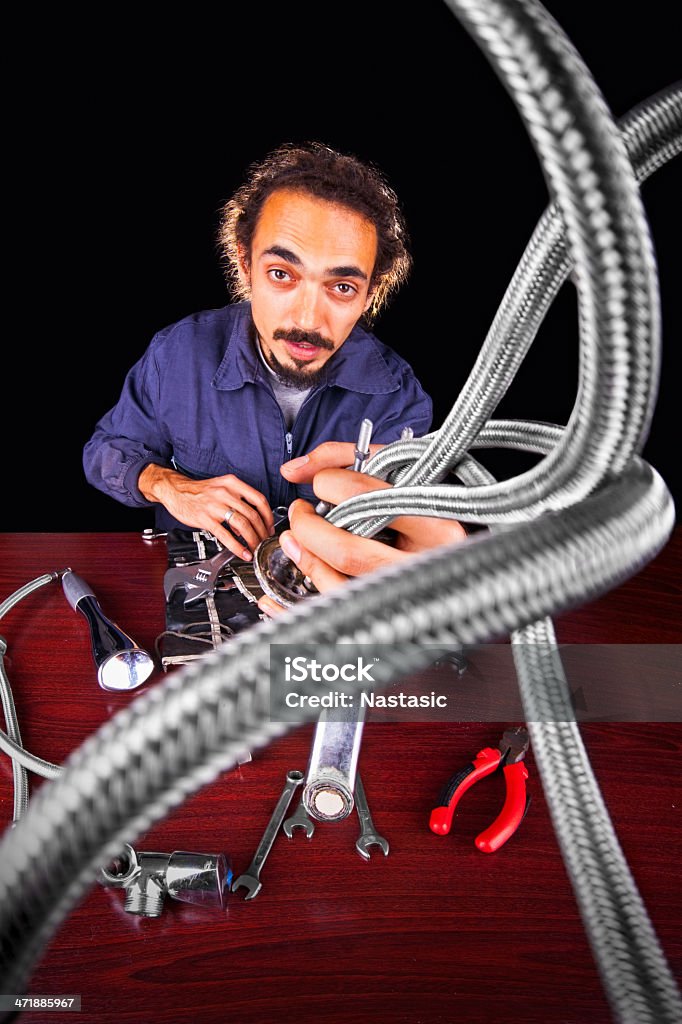 Repair man Young repairman with dreadlocks fixing Plumbing problems holding tubes ,isolated on black Serving Tongs Stock Photo