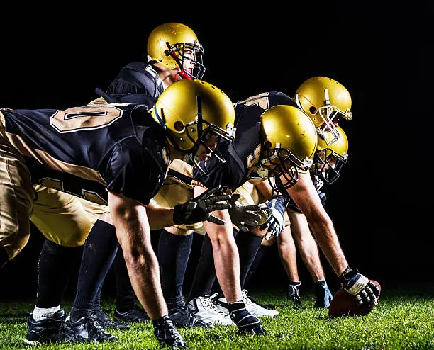 American football players taking their position at night.   