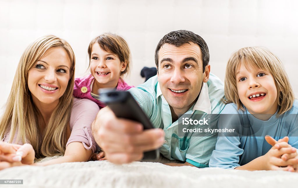 Allegra famiglia guardando la TV. - Foto stock royalty-free di Abbigliamento casual