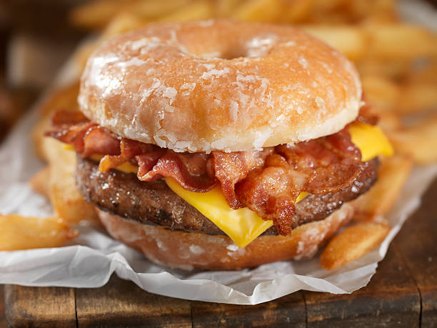 Glazed Donut Bacon Cheeseburger The Burger lovers brunch! It sounds like an odd combination but it tastes as good as it looks. It has also been a huge hit this summer across the US and Canada at Carnivals, State Fairs and even a few Food Trucks.-Photographed on Hasselblad H3D2-39mb Camera bacon cheeseburger stock pictures, royalty-free photos & images