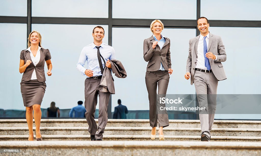 Cheerful business people outdoors. Four cheerful business people outdoors running down the stairs.   30-39 Years Stock Photo