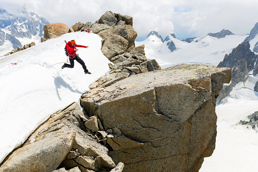 Mid air hiker engaging in a risky  jump on rock in the Fernch Alps