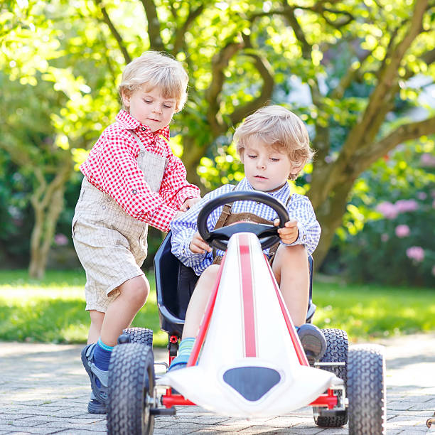 istock Two little sibling boys playing with pedal car 471889010