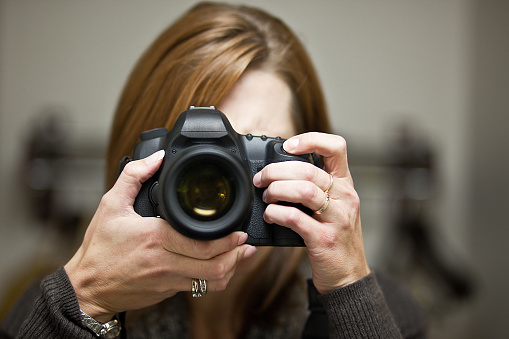 An image of a woman taking a photo with her DSLR camera.
