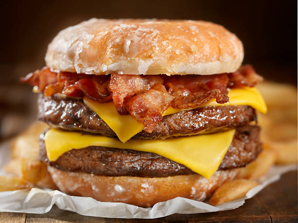 Glazed Donut Bacon Cheeseburger The Burger lovers brunch! It sounds like an odd combination but it tastes as good as it looks. It has also been a huge hit this summer across the US and Canada at Carnivals, State Fairs and even a few Food Trucks.-Photographed on Hasselblad H3D2-39mb Camera bacon cheeseburger stock pictures, royalty-free photos & images
