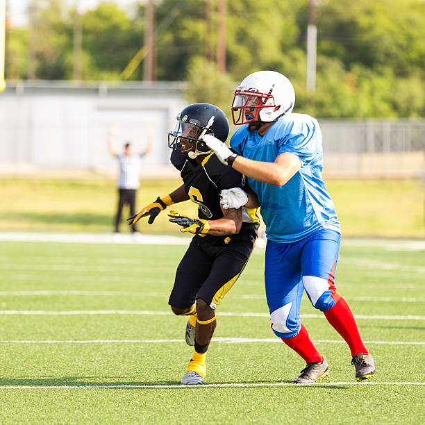 jogador de futebol americano correndo de intercepção durante o jogo - football player group of people running american football - fotografias e filmes do acervo