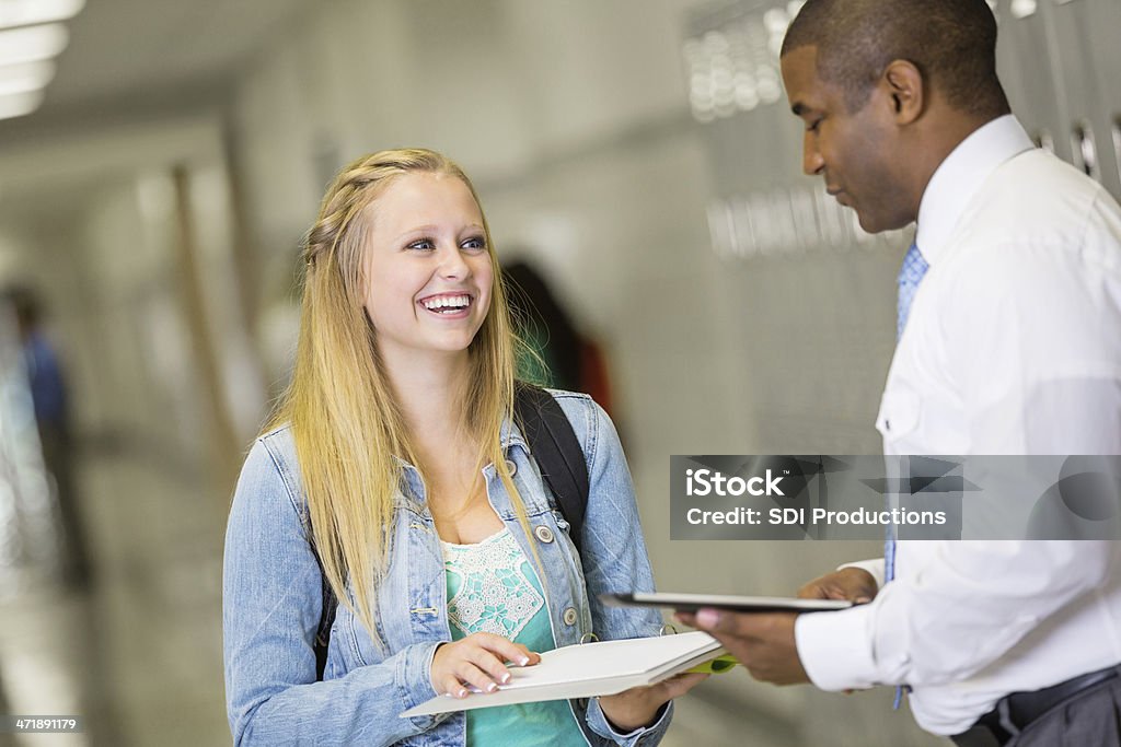 High school girl talking con el profesor en pasillo cerca de casilleros - Foto de stock de Adolescencia libre de derechos