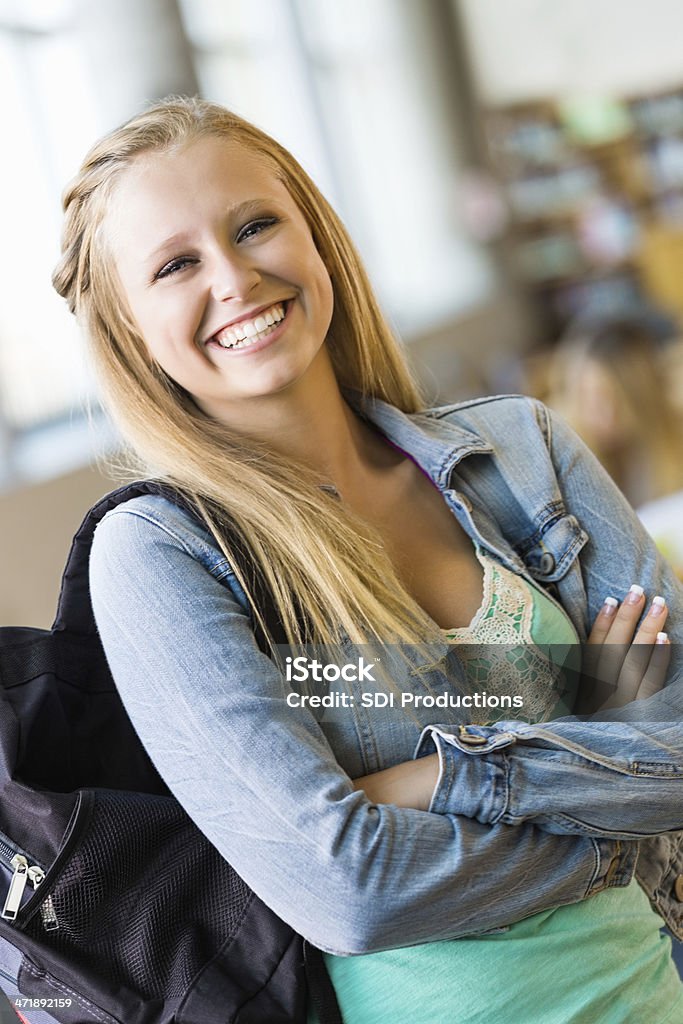 Escuela secundaria feliz Chica sonriente en biblioteca con mochila - Foto de stock de Adolescencia libre de derechos