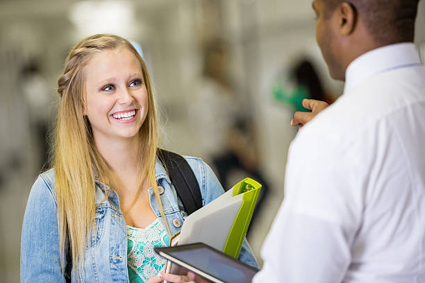 High school teacher talking to student after class in hallway