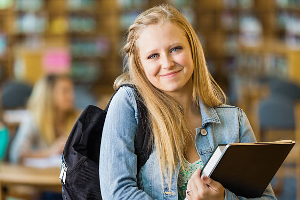 istock Cute high school student holding books in library 471893871