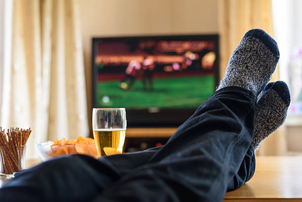 istock TV watching (football match) with feet on table and snacks 471894264