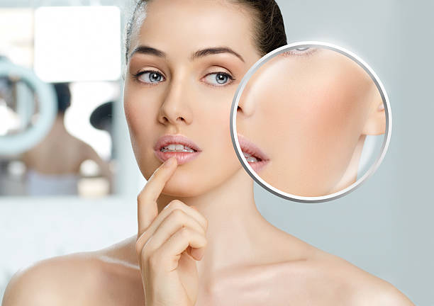 istock Bare faced woman looking closely at her face in a mirror 471896477