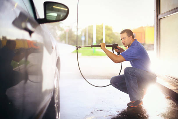 istock Man washing his car with hose sprayer. 471896766