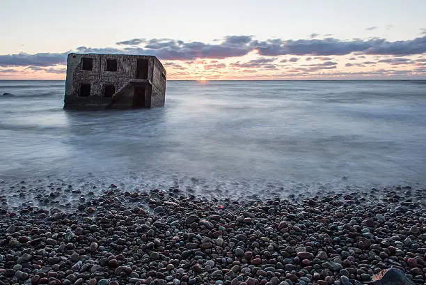 Photo of waves crushing over rocks in sunset