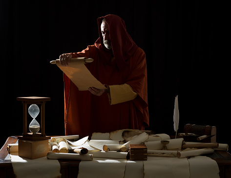 Medieval philosopher reading scrolls in dark
