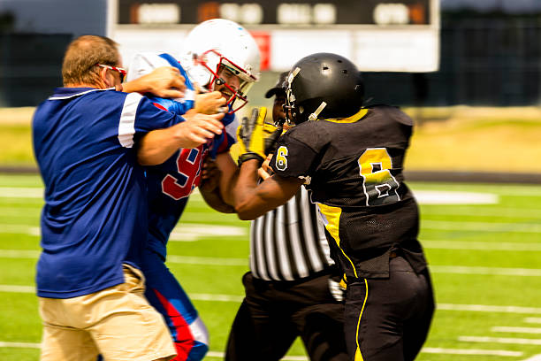 Determined American football player making a touchdown while passing through defensive players on playing field. Black and white photography.