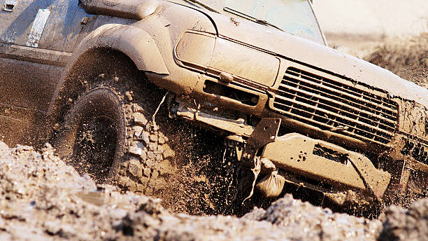 Sport utility vehicle on dirt road A very muddy SUV driving in mud while more mud splashes up from around the front tires.  The front of the SUV is shown. cable winch stock pictures, royalty-free photos & images