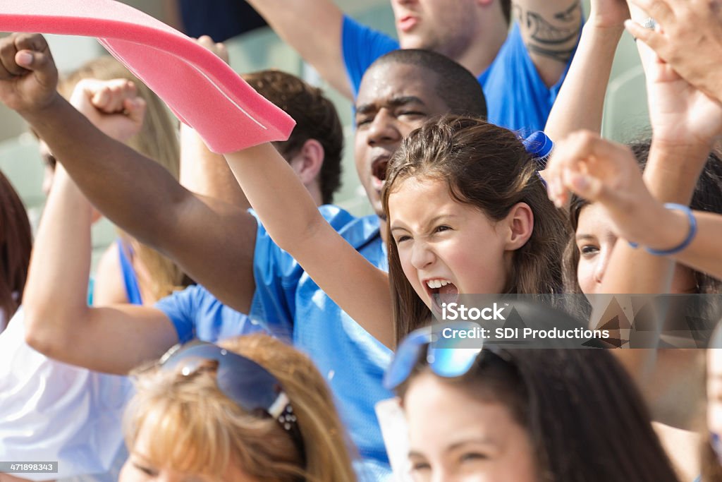 Маленькая девочка размахивающий лапами пены паль�цем и радость в Стадион толпы - Стоковые фото Ликовать роялти-фри