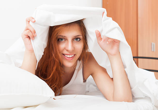 istock Smiling cute girl under the white sheets in bad 471900093
