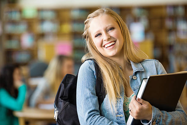 istock Happy high school student holding books in library after class 471900727