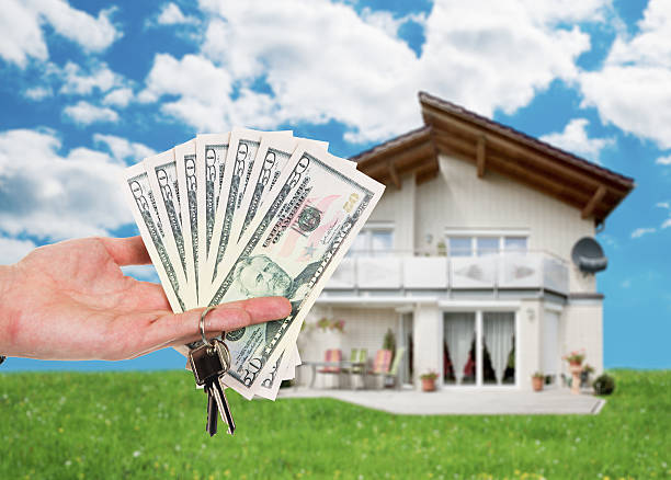istock Hand Holding Key And Dollar Notes Against House 471901664
